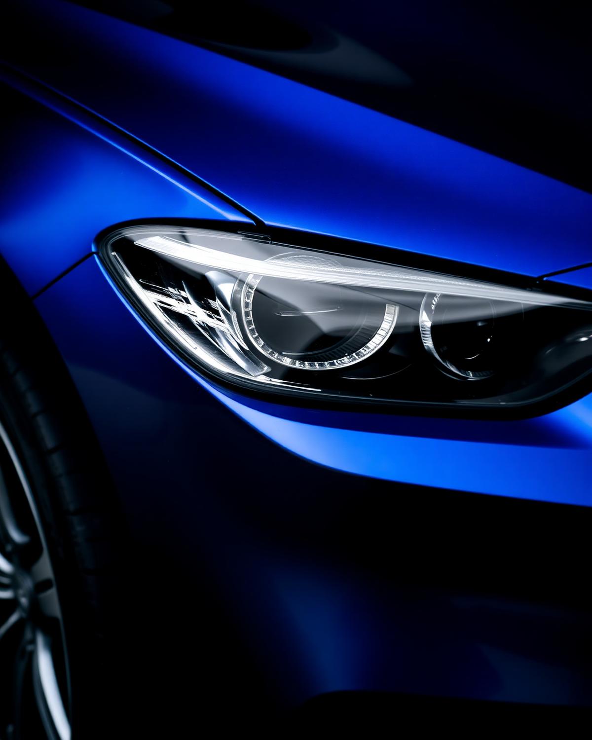 Close-up of a detailed vehicle headlight and glossy paint